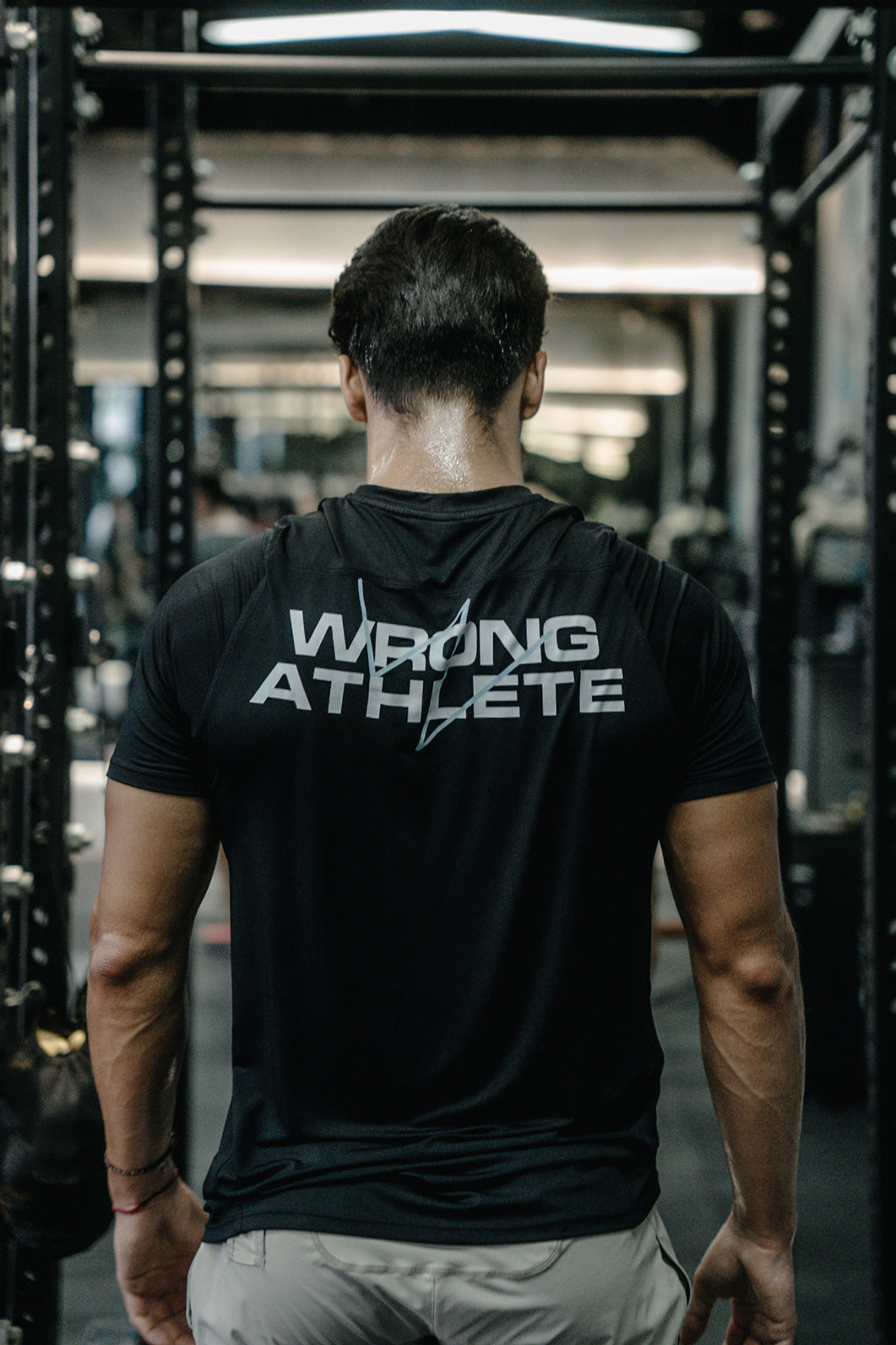 Male athlete from behind wearing a 'Wrong Athlete' shirt inside Wrong Gym Bali’s training facility.