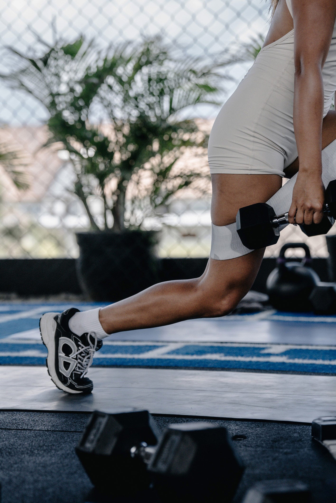 Female athlete in a lunge position holding dumbbells during a booty-focused class at Wrong Gym Bali.