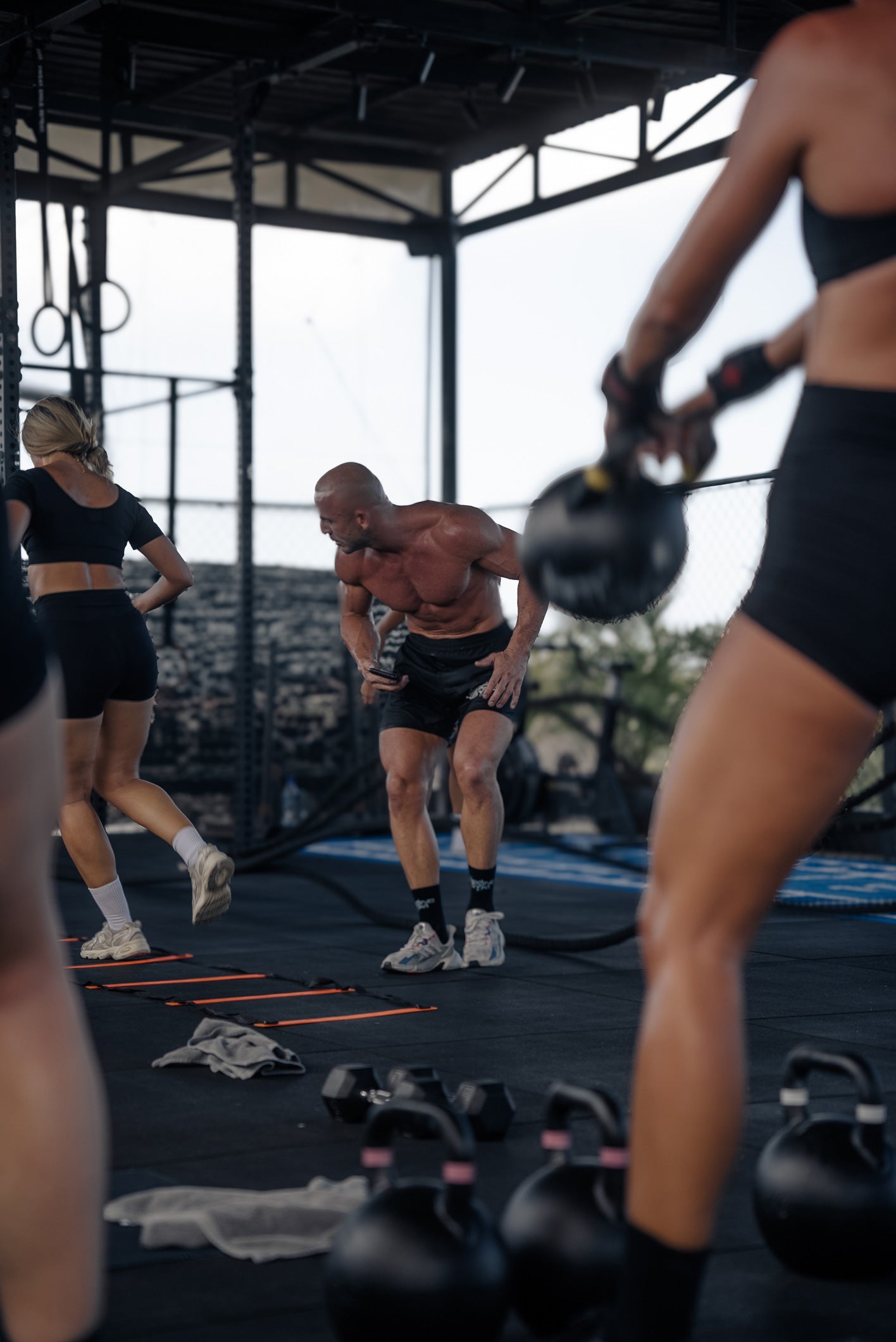 Coach Paul leads an intense hybrid training session at Wrong Gym Bali, guiding members through kettlebell and agility ladder drills on the rooftop training area.