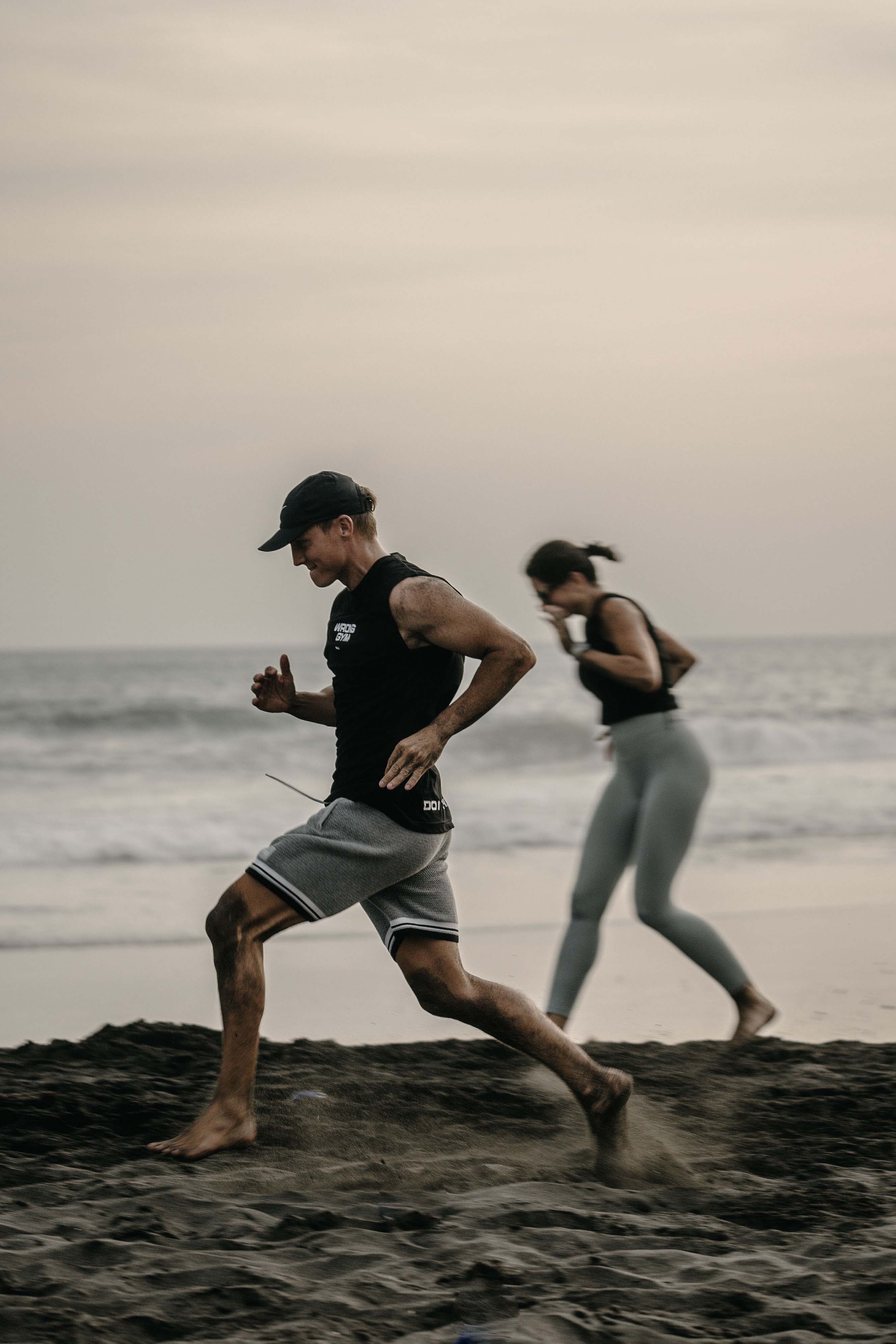 Fitness enthusiasts sprinting on the sand during a sunset beach bootcamp hosted by Wrong Gym Bali at Pererenan Beach.