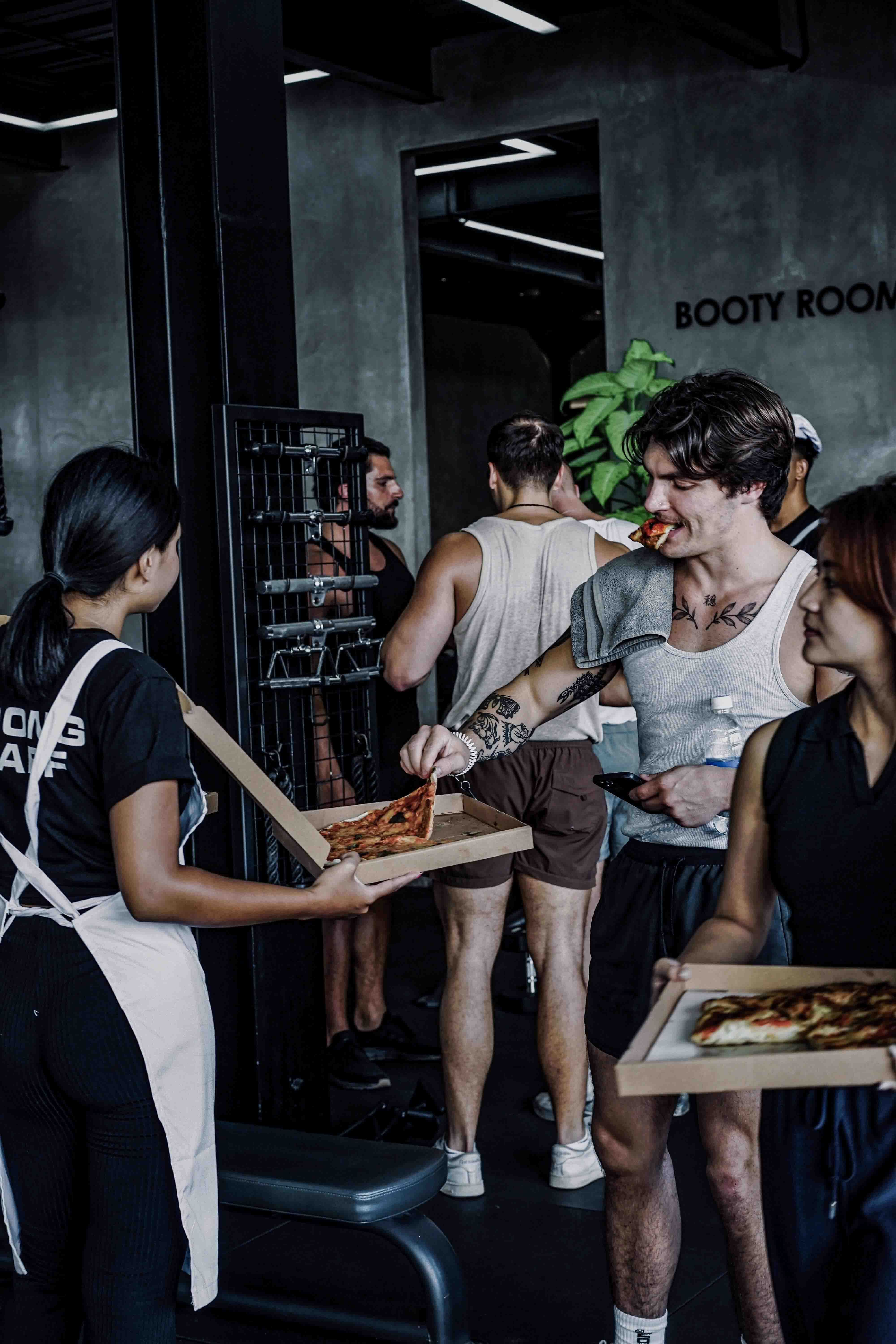 Gymgoers enjoying post-workout pizza during 'The Italian Job' event at Wrong Gym Bali, blending fitness with fun food culture.