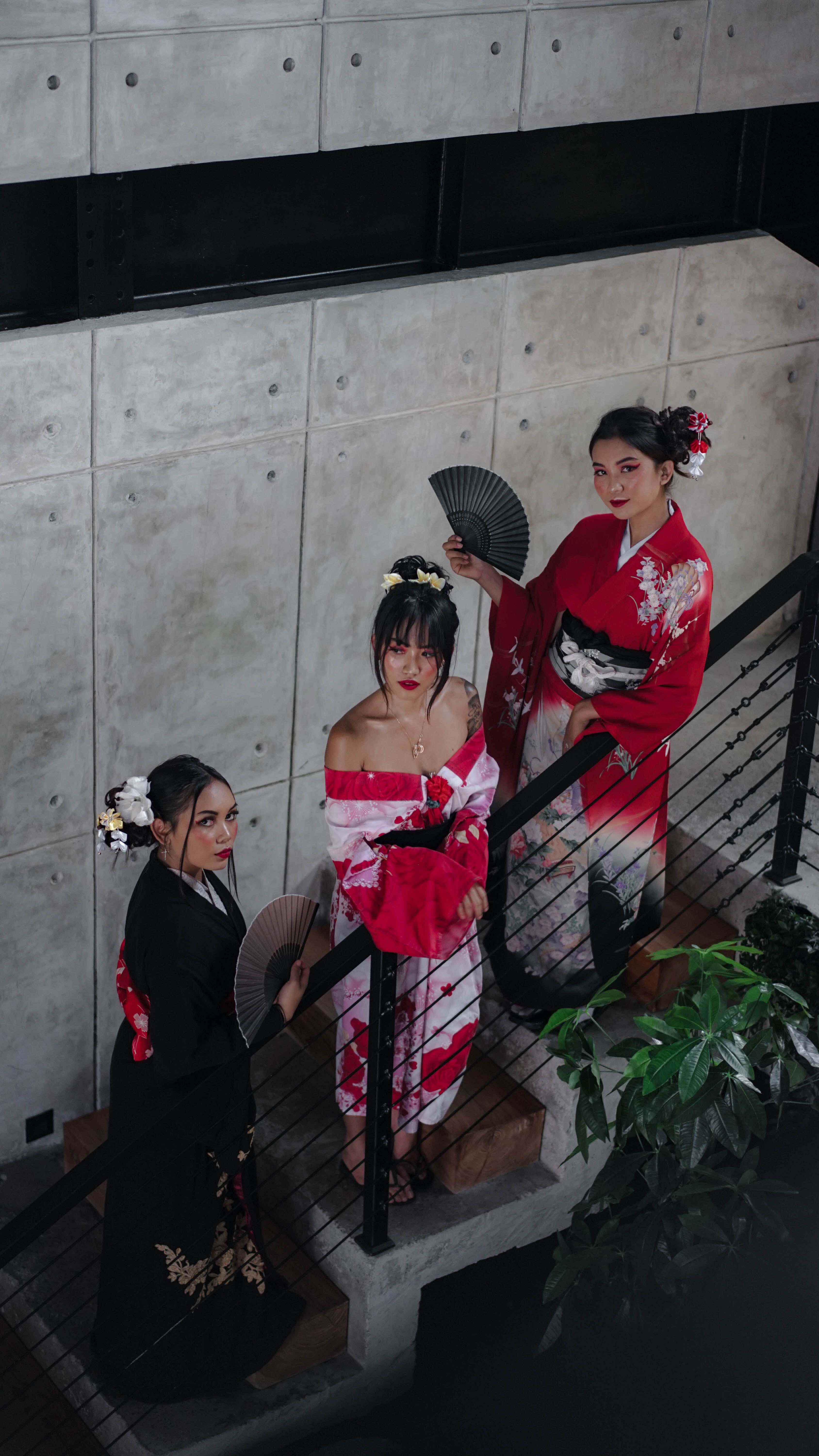 Three women in elegant Japanese-inspired attire pose with hand fans during 'Too Wrong to Handle' event at Wrong Gym Bali, celebrating cultural flair and creativity.