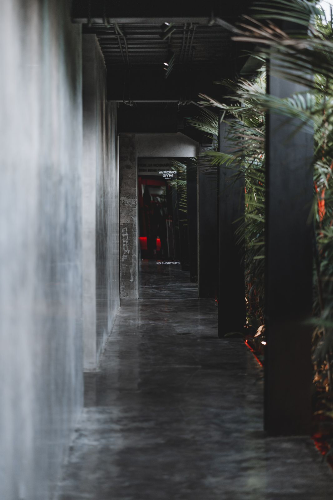 Moody concrete hallway at Wrong Gym Bali leading to the Hell Room entrance with 'No Shortcuts' sign on the door.