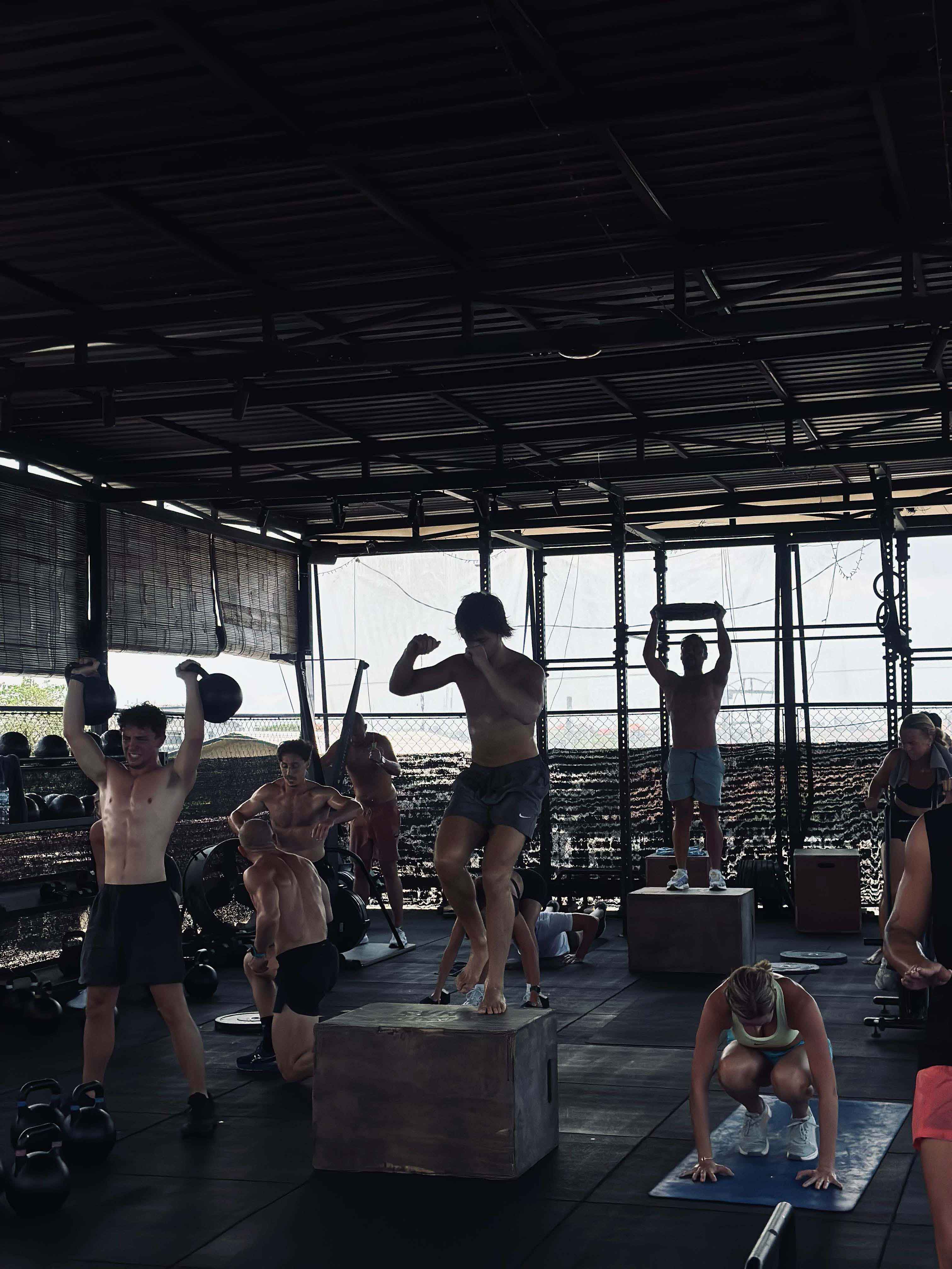 Group of fitness enthusiasts engaged in an intense Savage Saturday HIIT class at Wrong Gym Bali, featuring box jumps, kettlebell lifts, and burpees in an open-air training space.