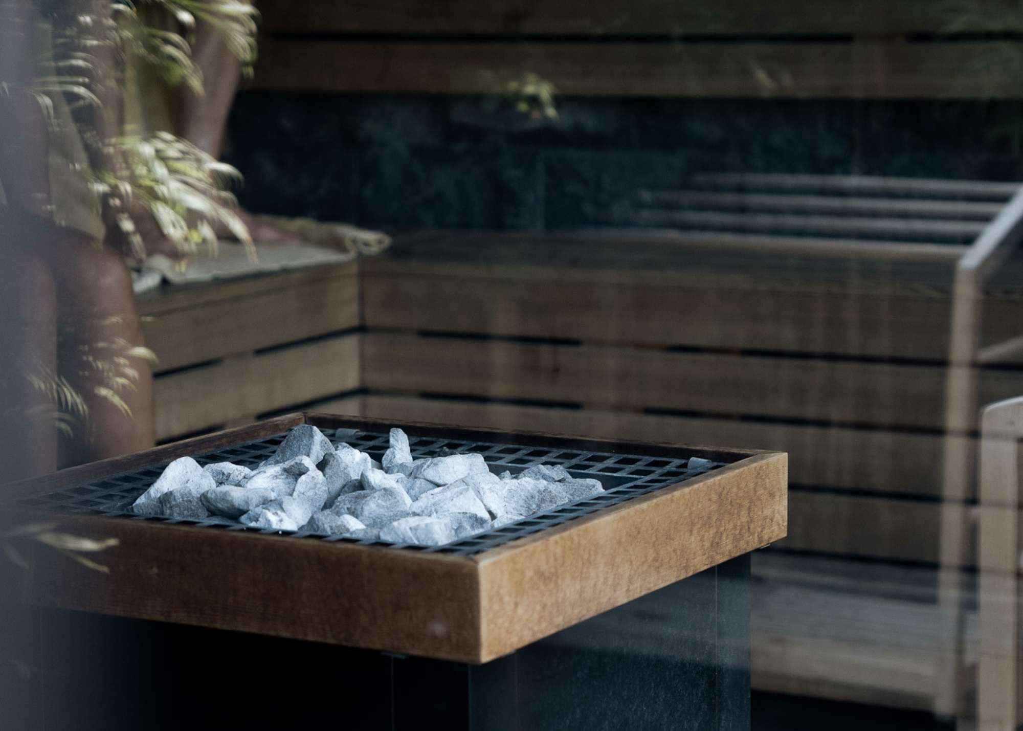 Close-up of a modern sauna heater with white stones inside Wrong Gym Bali’s wellness area, surrounded by wooden benches and calming interior details.