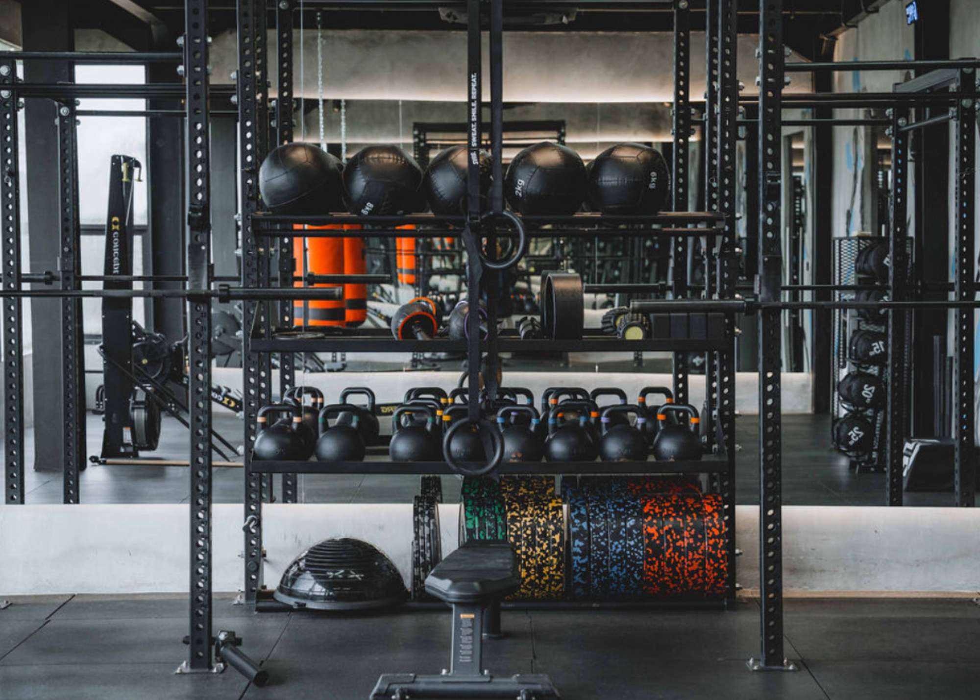 Organised rack of kettlebells, slam balls, resistance bands, and gym rings at Wrong Gym Bali’s functional training zone, reflected in a full-length mirror.