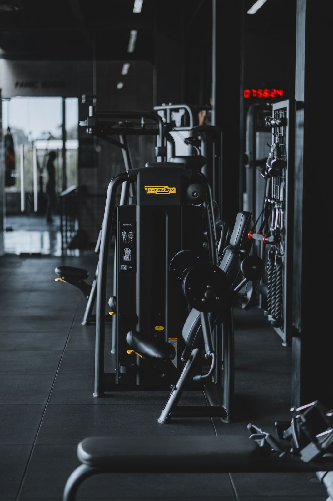 Technogym strength training machine in the open gym area at Wrong Gym Bali, with modern equipment and dark-toned interior.