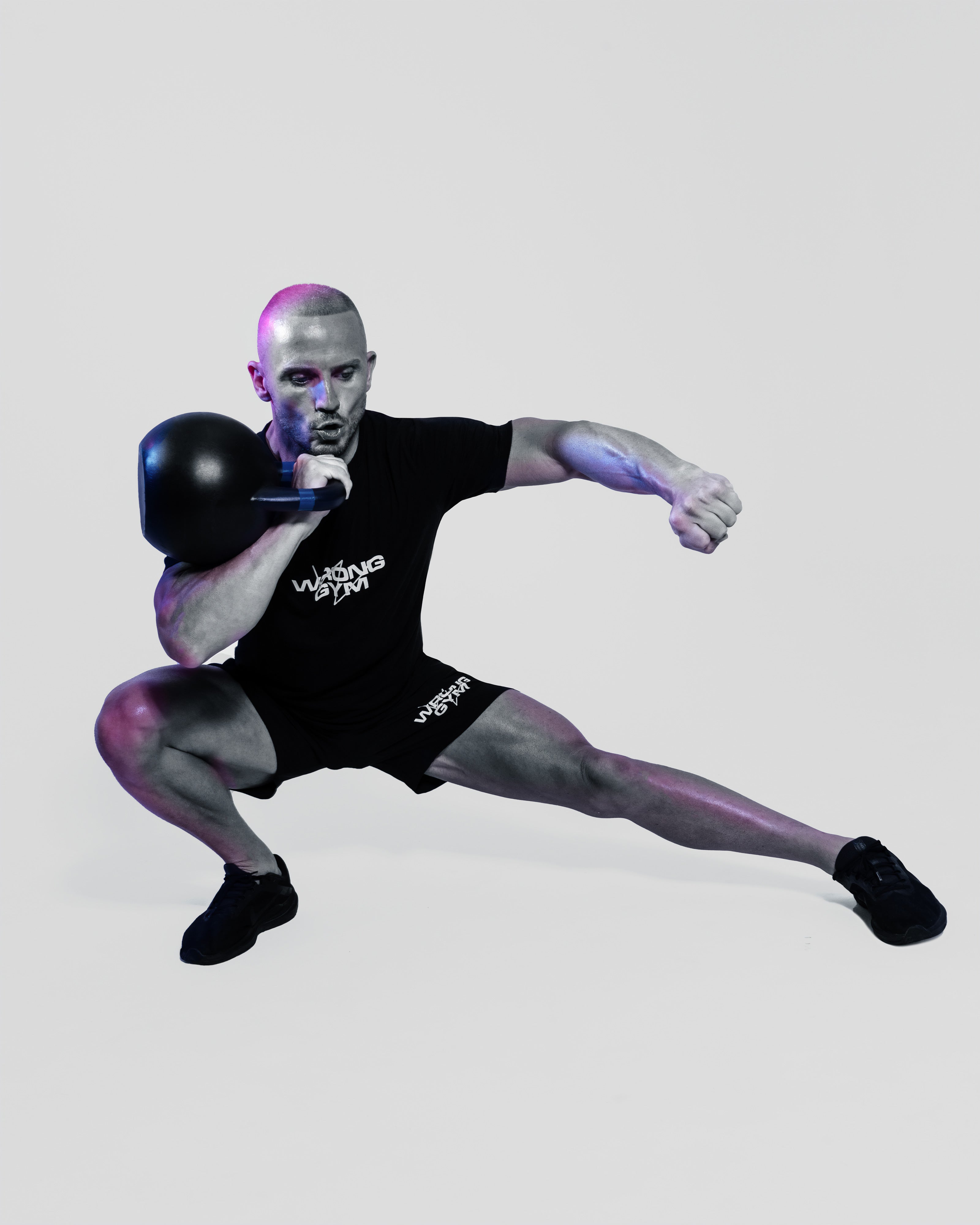 Personal trainer at Wrong Gym Bali performing kettlebell lateral lunge in studio setup.