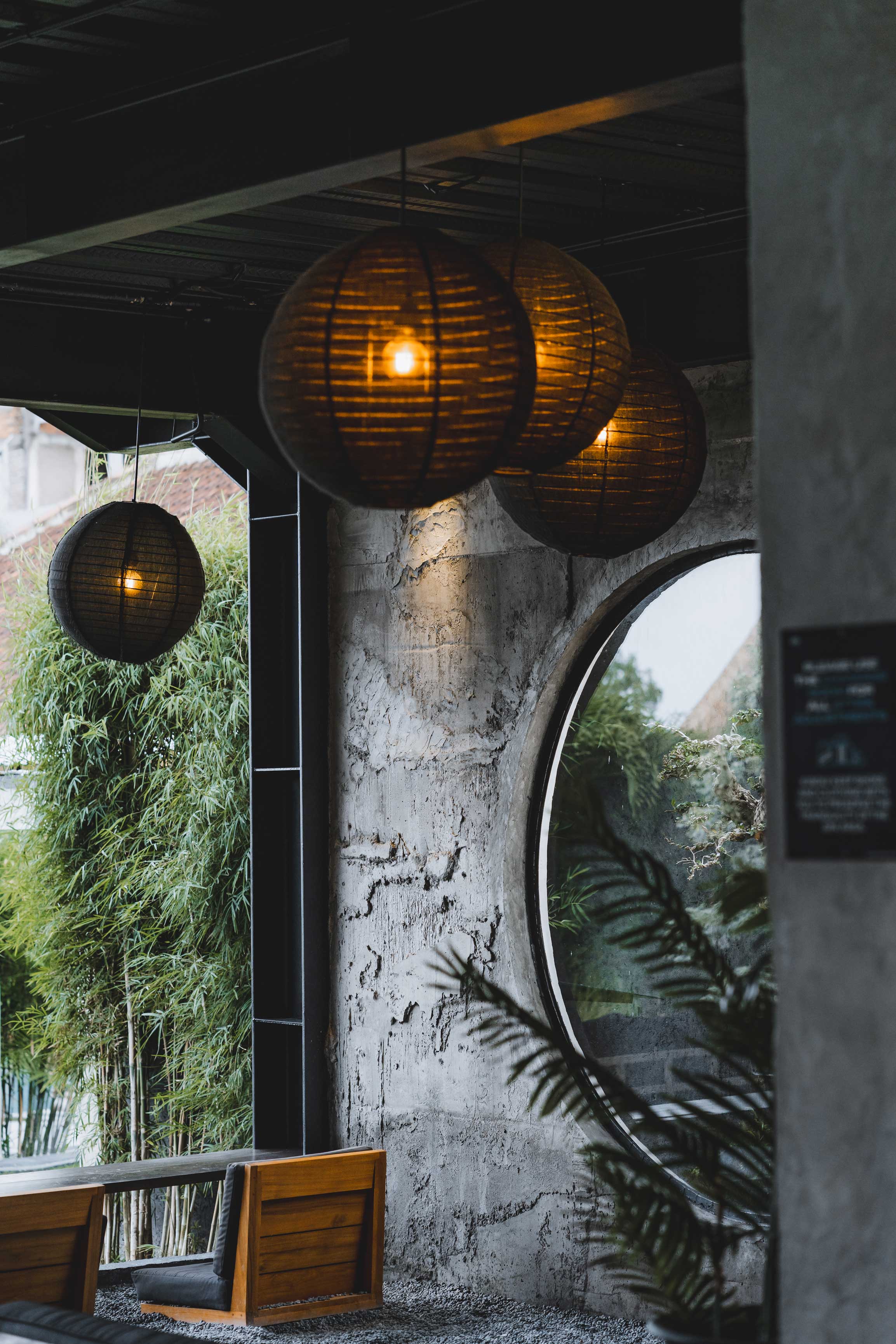 Cozy spa lounge area at Wrong Gym Bali featuring bamboo, circular window, and warm hanging lights.