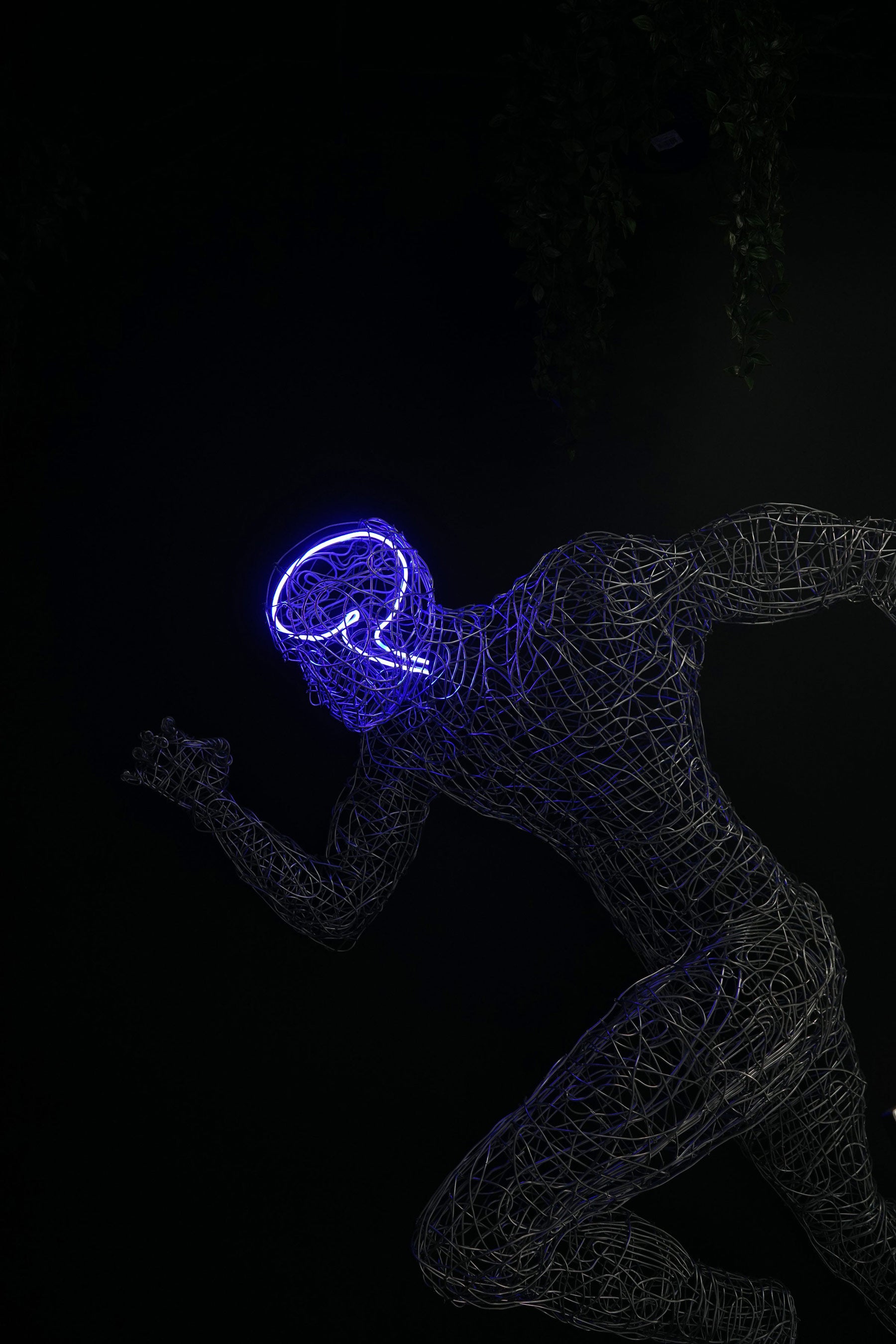 Wireframe sculpture of a running human figure with a glowing neon brain installation, featured in the dark ambient interior of The Lab at Wrong Gym Bali.