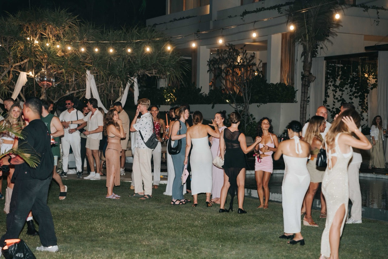 Guests socialising at the Wrong Gym Bali Oshom event, an outdoor evening gathering with lights and tropical decor.