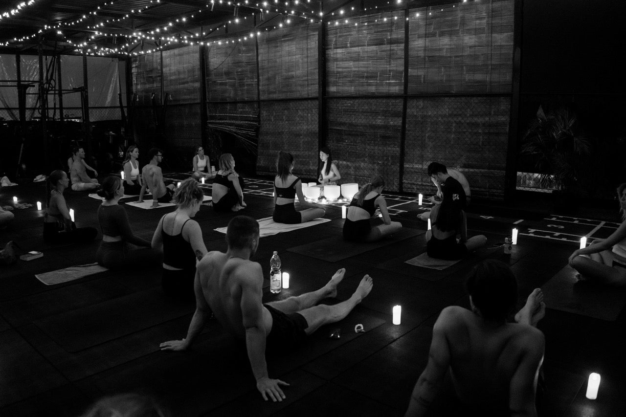 Participants seated on mats during candlelit wellness night featuring sound healing at Wrong Gym Bali.