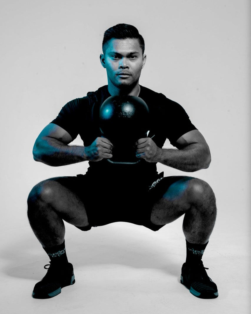 Wrong Gym Bali coach holding a kettlebell in deep squat position, demonstrating glute-focused strength training.