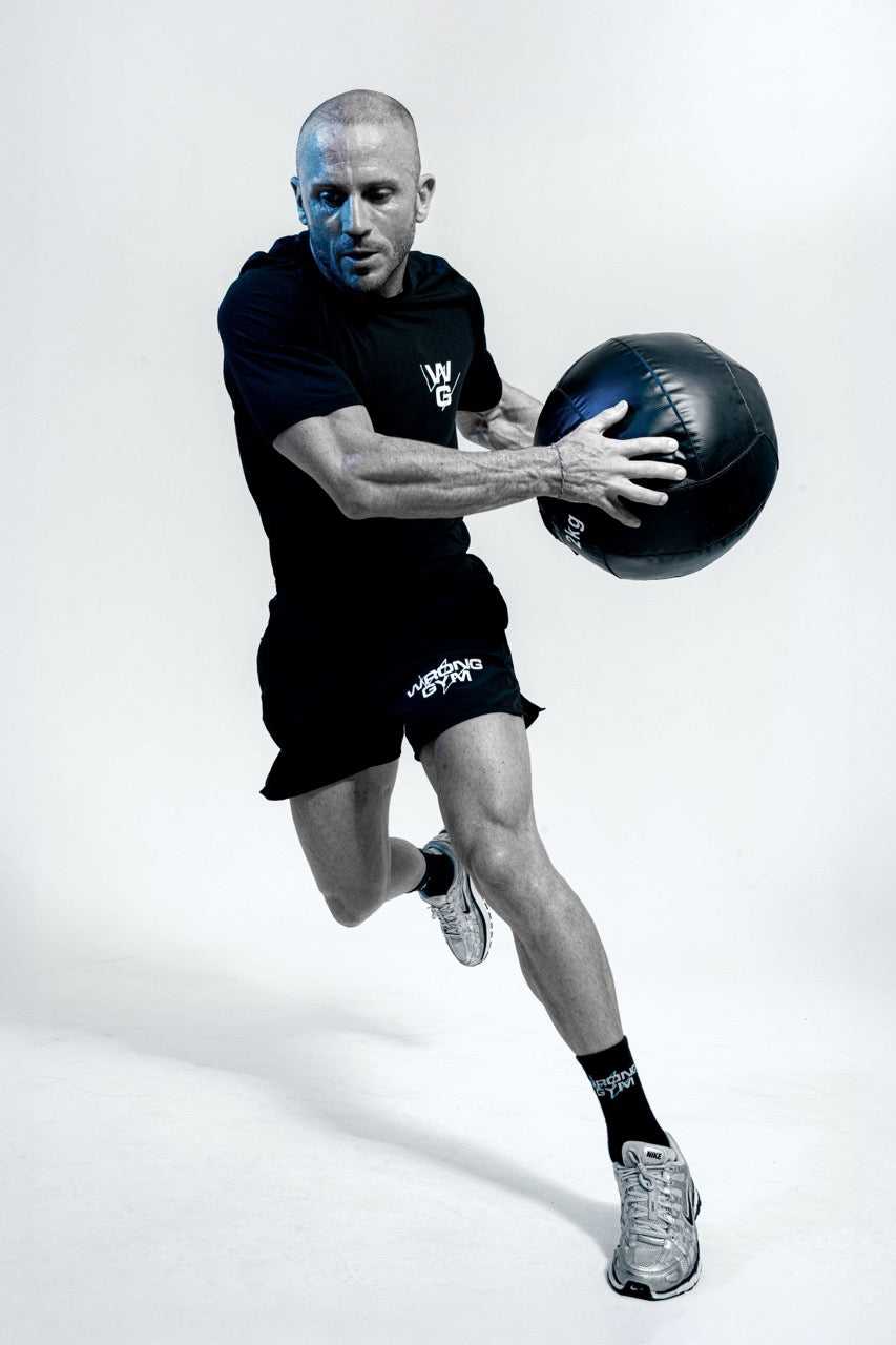 Wrong Gym Bali hybrid coach Paul in motion holding a medicine ball, showcasing athletic conditioning and functional strength.