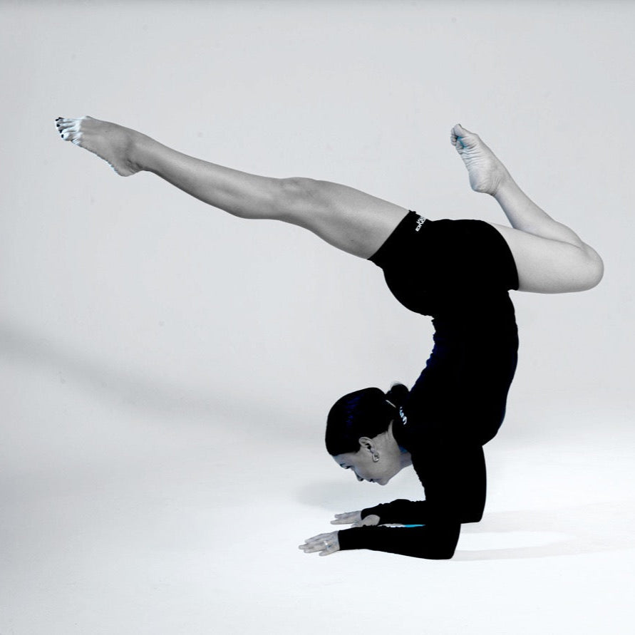 Wrong Gym Bali yoga trainer Polina performing a forearm balance with split legs, showcasing strength and flexibility.