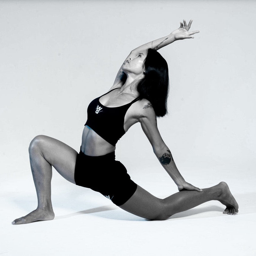 Wrong Gym Bali yoga coach Vena demonstrating a graceful standing balance pose with arms extended overhead