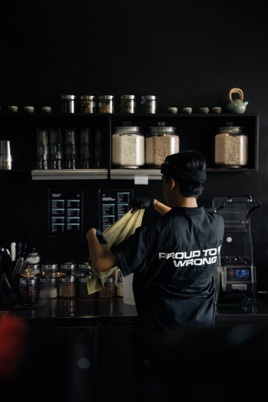 A man wearing a black shirt stands in front of a counter, mistakenly identified as gym bar staff