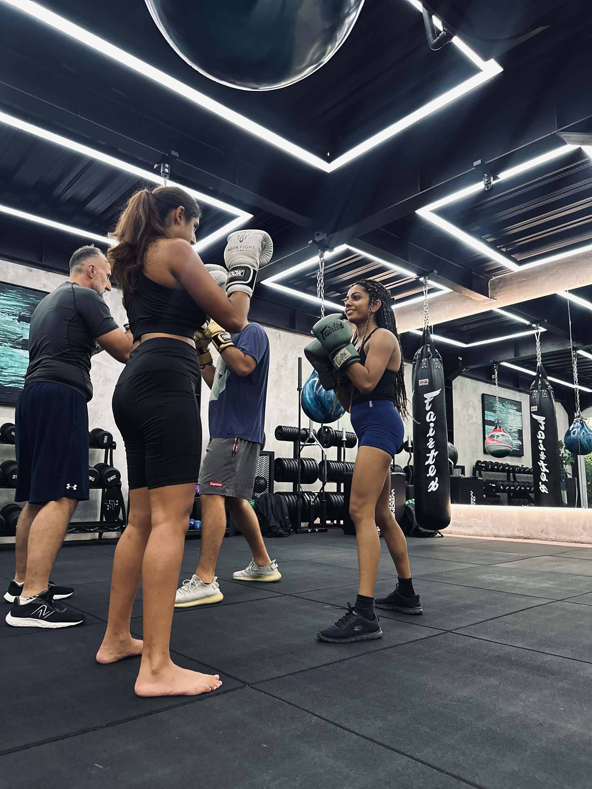 Group of adults engaged in partner boxing drills at Wrong Gym Bali's Fight Club class, wearing gloves and training in a modern gym setting.