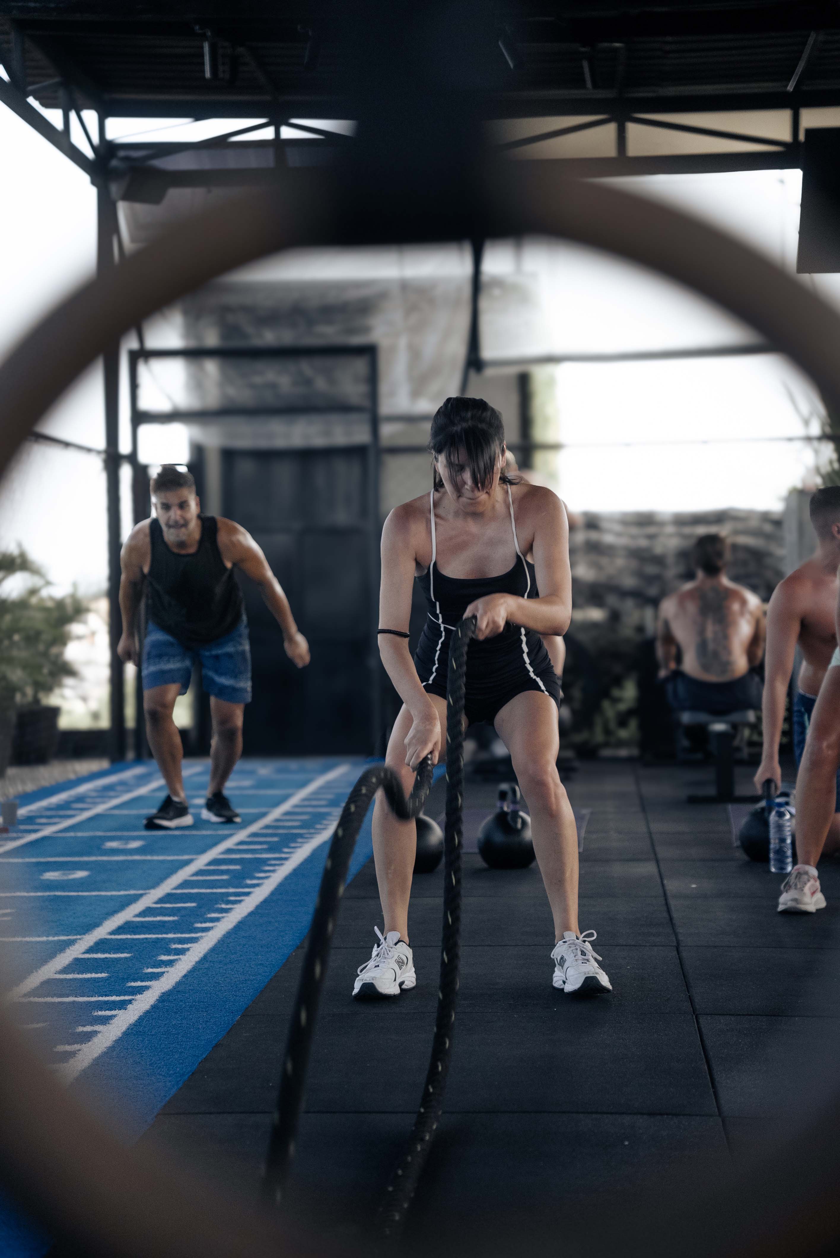 Participants in a high-energy hybrid HIIT training session at Wrong Gym Bali performing battle rope and agility drills in a semi-outdoor fitness space.