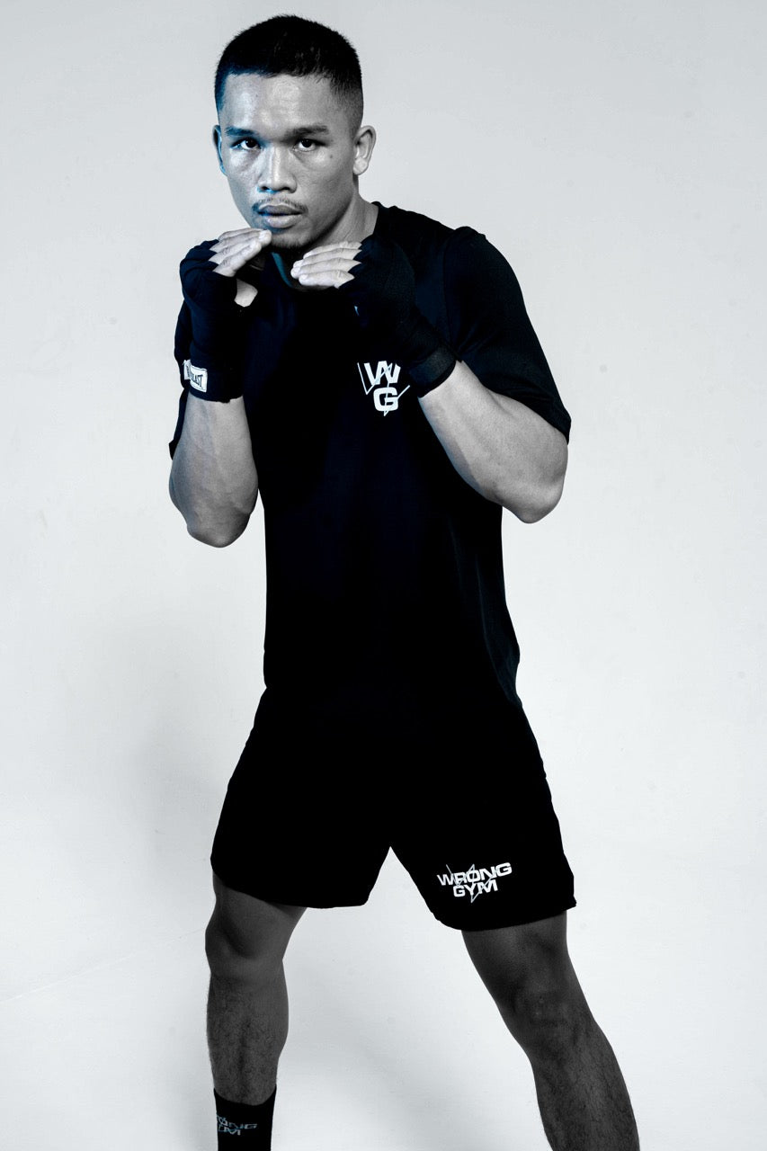 Wrong Gym Bali boxing coach Cakti in fighting stance, wearing branded gloves and gear, ready for combat training.
